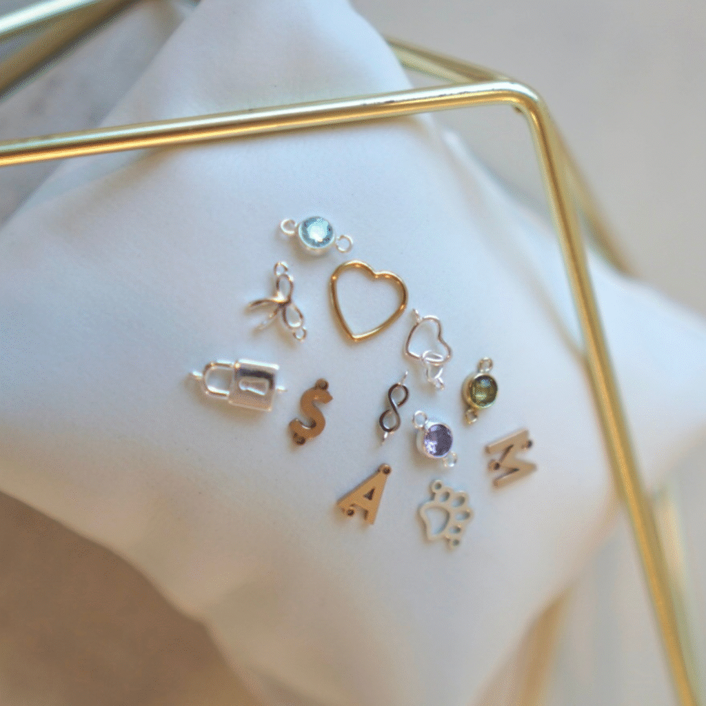 Assortment of dainty charms and connectors laid out beside chain options.